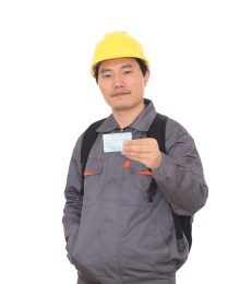农民工背着书包头戴黄色安全帽手拿回家过年的火车票