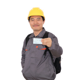 农民工背着书包头戴黄色安全帽手拿回家过年的火车票