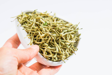 手拿着装有金银花茶的白瓷茶荷