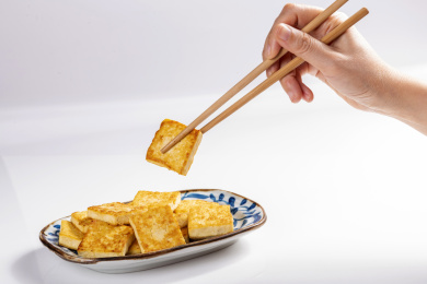 女性手持筷子夹起炸豆腐煎豆腐特写