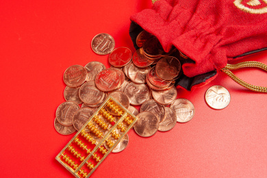 红色背景钱袋硬币和算盘静物