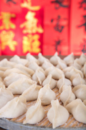 春联红背景前的托盘上包好待煮的白面饺子