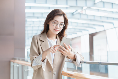 年轻亚洲商务人士靠着栏杆在看手机