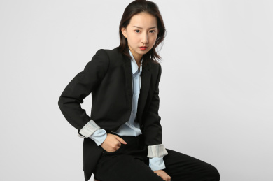身穿正装的年轻女人坐在白色墙前