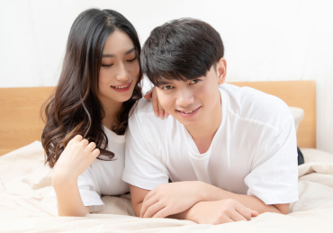  穿着白色短袖趴在床上的一对亚洲年轻情侣