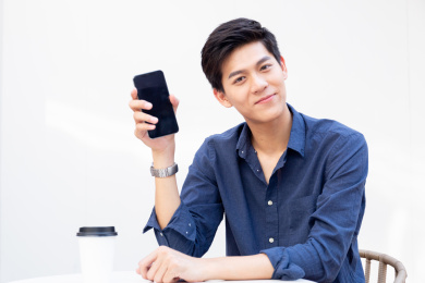 举着手机正面看着镜头的年轻人