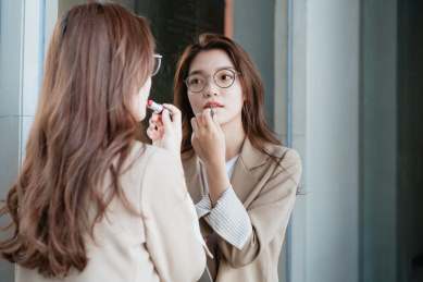 年轻亚洲商务人士对着镜子补妆画口红