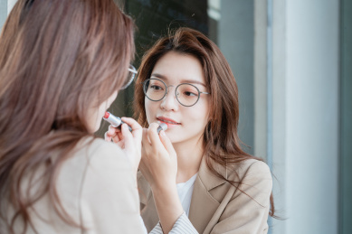 年轻亚洲商务人士对着镜子补妆画口红
