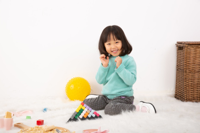 坐在地上玩金字塔玩具的小女孩