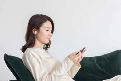 年轻女士坐在沙发上使用手机