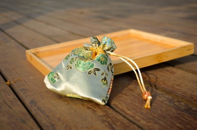 放在原木色盘子旁的米白色刺绣锦囊