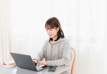 短发女生坐在桌子边使用笔记本电脑