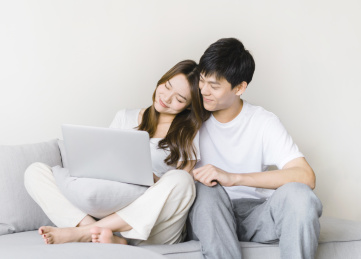 甜蜜的情侣一起坐在沙发上看笔记本电脑