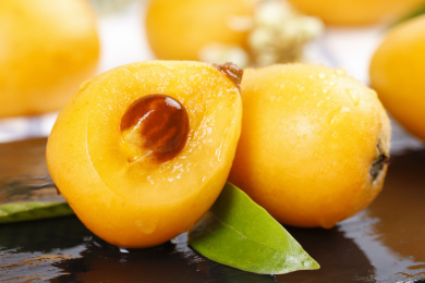 黑底上放着枇杷和枇杷果肉