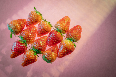 粉色背景前整齐排列着的草莓俯视图