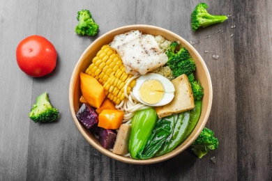 暗色木纹桌面上放着一盘轻食健康餐蔬菜