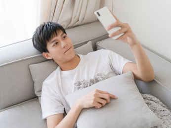 年轻的男生一个人在家里玩手机