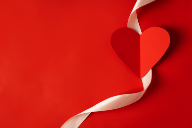 情人节红色背景上的香槟色带子放着一颗红心