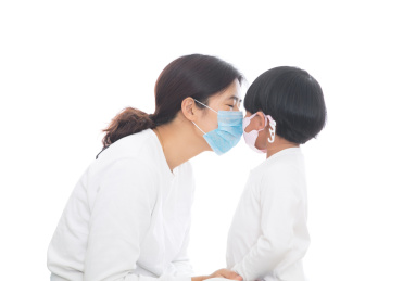 戴着口罩的妈妈在亲戴着口罩的女儿