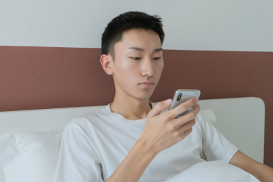 中国男人在卧室的床上玩手机