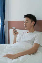 中国男人在卧室的床上玩手机
