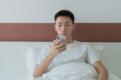 中国男人在卧室的床上玩手机