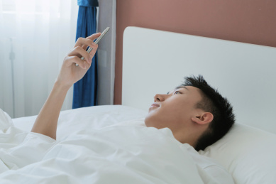 中国男人在卧室的床上玩手机