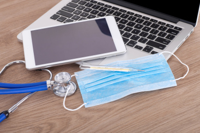 笔记本电脑上的iPad和口罩及水银温度计