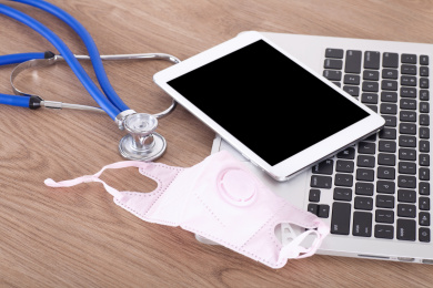 笔记本电脑上的iPad和口罩及旁边的听诊