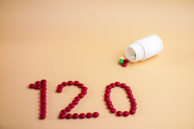 用药片拼成的数字120放在纯色背景中