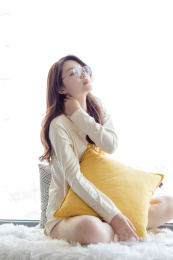 一名戴着眼镜的年轻女性在窗台上按摩脖子