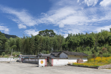 蓝天白云下竹林前的一座祠堂侧面及水泥空地