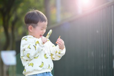 拿着放大镜大笑探索发现的小男孩
