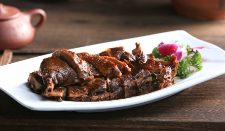 深色木托盘上白色条盘里的酱板鸭