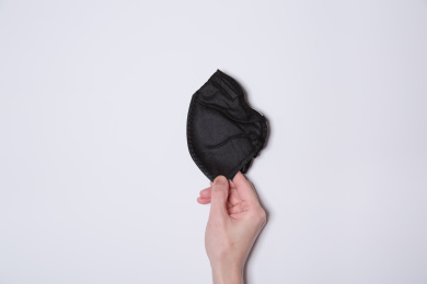 右手举着一只折叠着的黑色KN95口罩