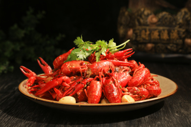 深色背景上一盘油焖大虾，上面点缀着香菜