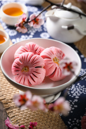 棉麻茶巾上用白色盘子装的粉色梅花酥