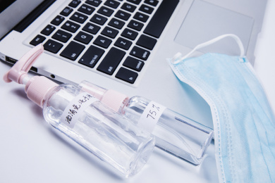 双手在笔记本上操作旁边放着一些消毒用品