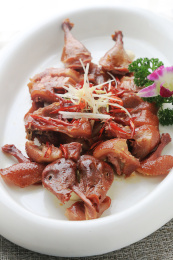 浅灰色餐布上白色椭圆瓷盘里的烤鸭