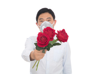 戴口罩的男士手拿红玫瑰在白背景前