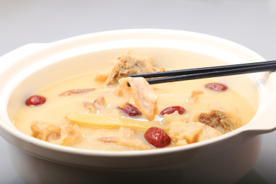 灰色背景上白色砂锅里的猪肚火锅