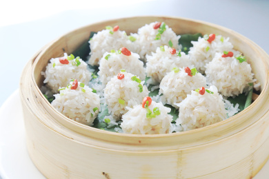 浅灰色背景上木蒸屉中的珍珠圆子