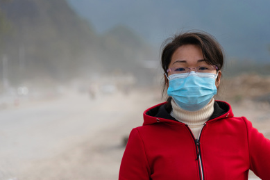 尘土飞扬的乡村道路背景前一个戴口罩的女士