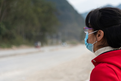 山区道路边一个侧身戴口罩的女士特写