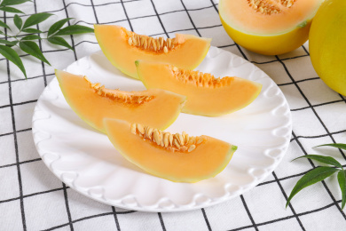 放在方格餐布背景上盘子里切开的黄金甜瓜