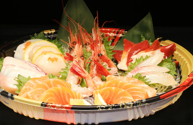 黑色背景上圆形日式打包盘中的刺身拼盘