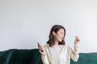 一名年轻女姓在客厅里使用无线耳机听音乐