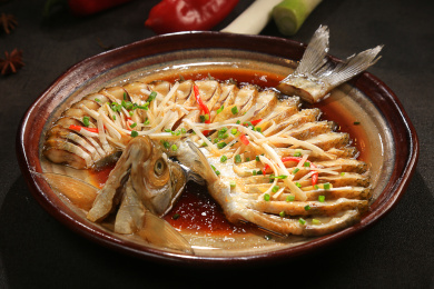 深灰色背景上暗红色陶盘中的清蒸武昌鱼