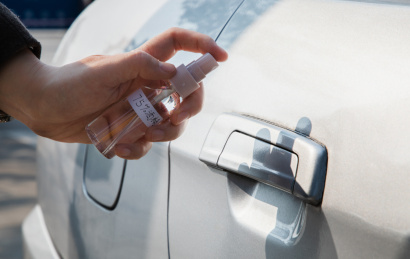 特写手拿着75度酒精喷车门把手