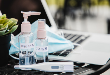 特写笔记本电脑旁边放着酒精口罩体温计等